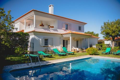 a villa with a swimming pool in front of a house at Casa do Marmeleiro Guest House Cascais in Cascais