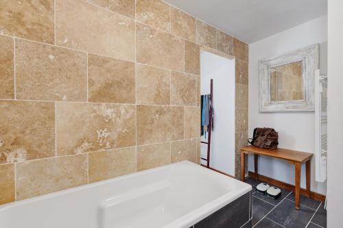 a bathroom with a tub and a tile wall at Villa Bleu Azur - piscine, plages in Angles