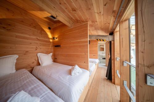 two beds in a room with wooden walls at Cabane Cala - Coeur d'Arcachon in Arcachon