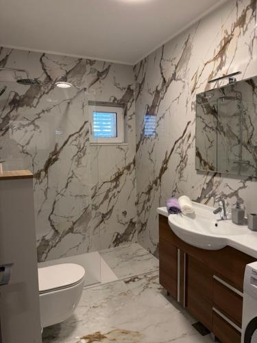 a bathroom with a marble wall at Apartman Kata in Šmrika