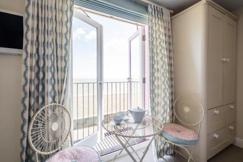 a room with a large window with a table and chairs at Magenta - A stunning Seafront house with lovely and uninterrupted Beach Views - Aldeburgh Coastal Cottages in Aldeburgh