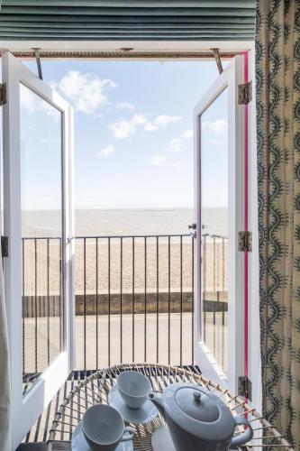 a room with a view of the beach from a balcony at Magenta - A stunning Seafront house with lovely and uninterrupted Beach Views - Aldeburgh Coastal Cottages in Aldeburgh