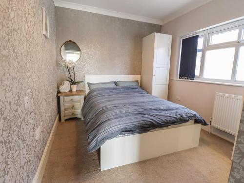 a bedroom with a bed and a mirror and a window at Sorrento in Mablethorpe