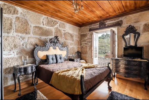 a bedroom with a bed and a stone wall at Villa Miranda Heritage House in Creixomil