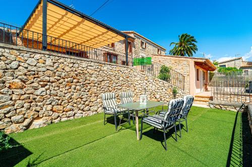 a patio with a table and chairs and a stone wall at Villa Sa Costa - Families or Couples Only in Calvià
