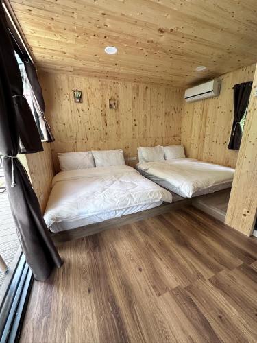 two beds in a room with wooden walls at 龜在銅三 in Tongluo