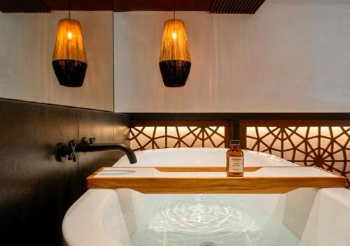 a bathroom with a tub and a bottle of whiskey at Villa Merida Luxury Mansion - Adults Only Boutique Hotel in Mérida