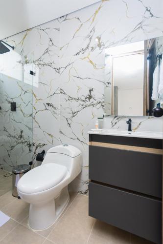 a bathroom with a toilet and a sink and a mirror at Hotel Distrito 70 Living in Medellín