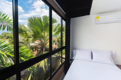 a room with a window with a bed and palm trees at Hotel Distrito 70 Living in Medellín