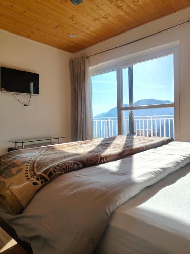 a large bed in a bedroom with a large window at Saadhan Homestay in Mussoorie