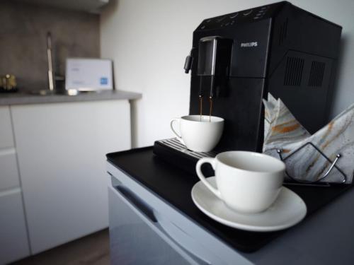 two cups on a counter with a coffee maker at ArSa in Ventspils