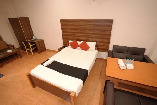 a small bedroom with a bed and a desk at JK Golden Embassy in Mysore