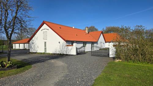 a white barn with an orange roof at Sov Godt i Arnborg Bed & Breakfast in Arnborg