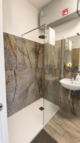 a bathroom with a glass shower and a sink at Modena Station - Suite H24 in Modena
