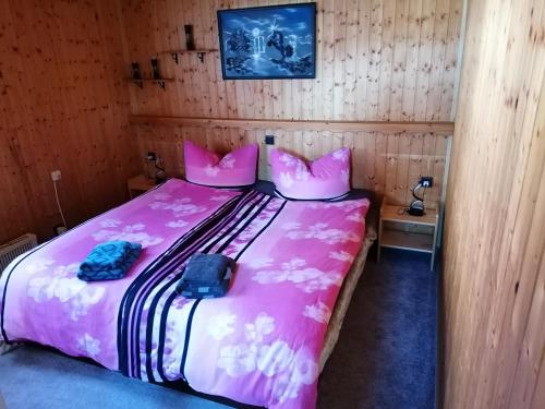 a bedroom with a pink bed with two bags on it at Ferienhaus Lisa in Klingenthal