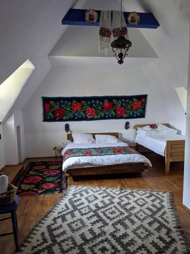 a bedroom with two beds and a rug at Maramureș Traditional House in Vadu Izei