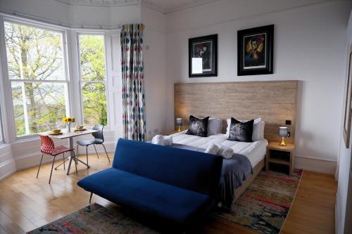 a bedroom with a large bed and a blue couch at The Clarendon in Dundee