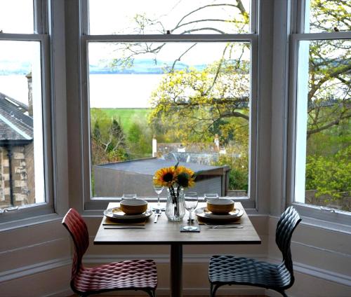 a table with a vase of flowers sitting in a room with windows at The Clarendon in Dundee