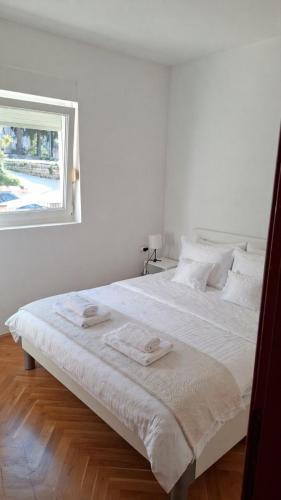a bedroom with a white bed with two towels on it at Sirius Apartment in Škaljari