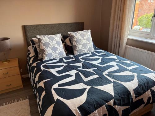 a bed with a blue and white comforter and pillows at Central Mablethorpe Apartment in Mablethorpe