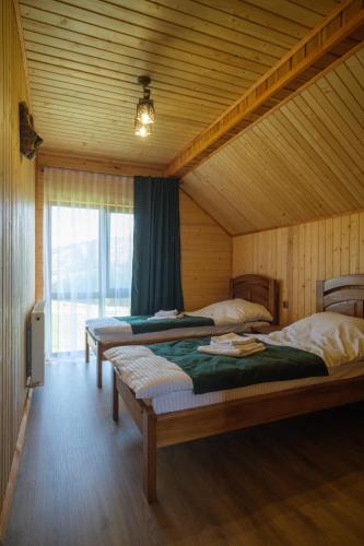 a bedroom with two beds in a wooden room at Шепіт Карпат in Yasinya
