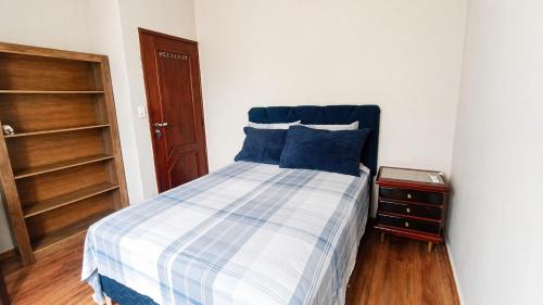 a bedroom with a bed with blue pillows and a night stand at Recanto Paraense in Belém