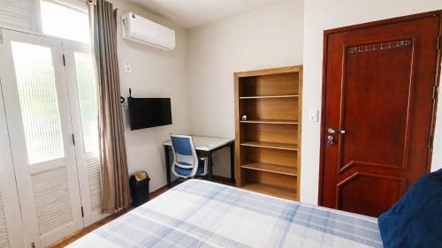 a bedroom with a bed and a desk and a window at Recanto Paraense in Belém