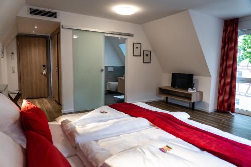 a bedroom with a large bed and a television at Altstadthotel Wilde Rose in Eppingen