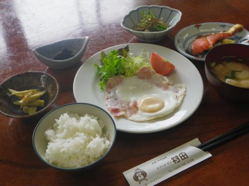 een tafel met een bord eten met rijst en groenten bij Resort Inn Murata in Iiyama