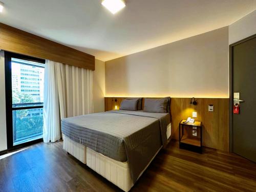 a bedroom with a large bed and a large window at Flat Executive City Jardins in São Paulo