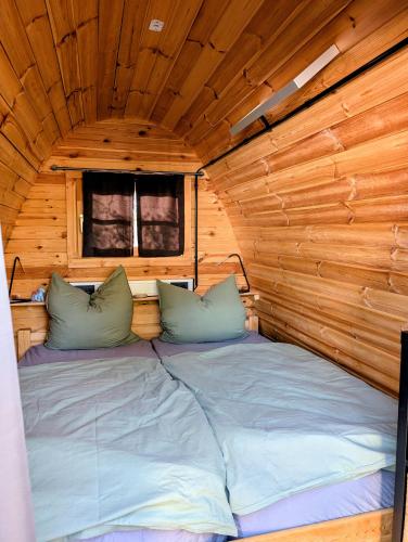 a bed in a wooden cabin with two pillows at Glamping im Tiny House - nahe Dresden in Freital