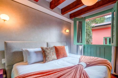 a bedroom with a bed with a window and a bedspread at Casa AcoModo at Casco Viejo 6BR Mansion w Pool in Panama City