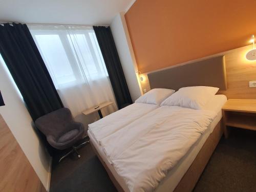 a bedroom with a bed and a chair and a window at Akdeniz Pension in Ludwigsfelde