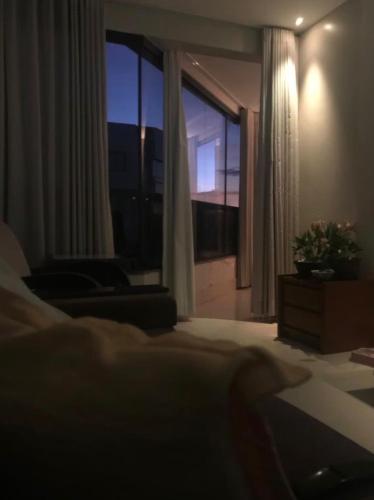 a bedroom with a bed and a large window at Quarto Sol in Brasília