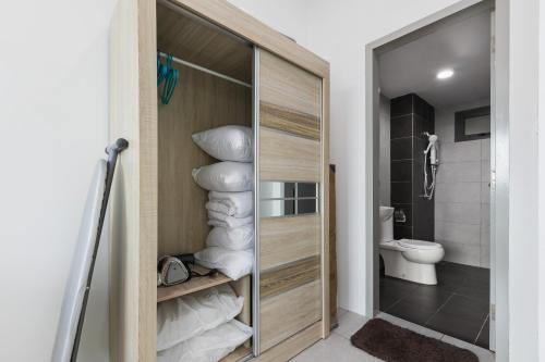 a bathroom with a toilet and a door with towels at Meritus Suites - 8pax in Perai