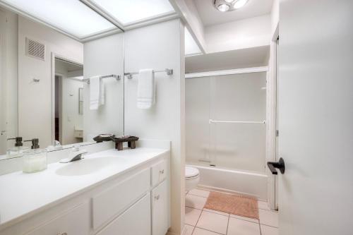 a white bathroom with a sink and a toilet at Oceanfront 2BR - Private Patio - Steps to Beach in Carlsbad