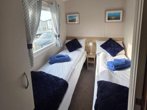 two beds in a small room with blue pillows at Pines 15 in Porthcawl