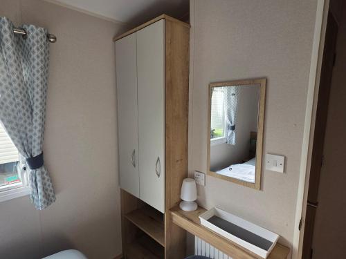 a bathroom with a mirror and a white cabinet at Pines 15 in Porthcawl