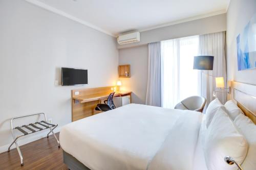 a hotel room with a white bed and a tv at Comfort Ibirapuera in São Paulo