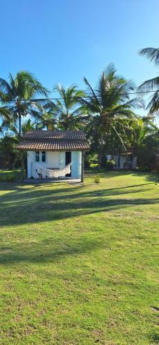 a small white house with palm trees in a field at Pousada Safyra in Caraíva
