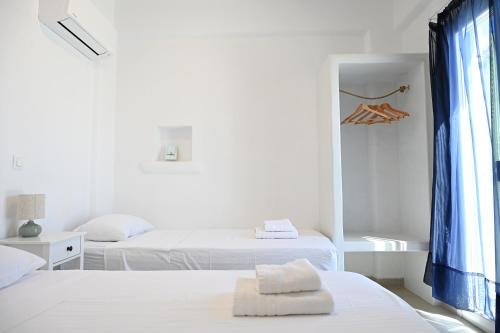 a white room with two beds and a window at Sto Faro - Green in Kithnos