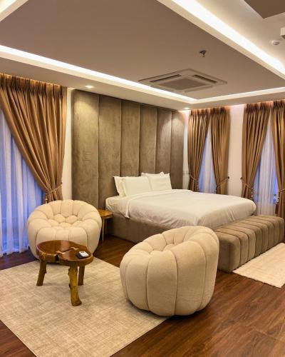 a bedroom with two beds and two chairs at The Mansion in Abuja