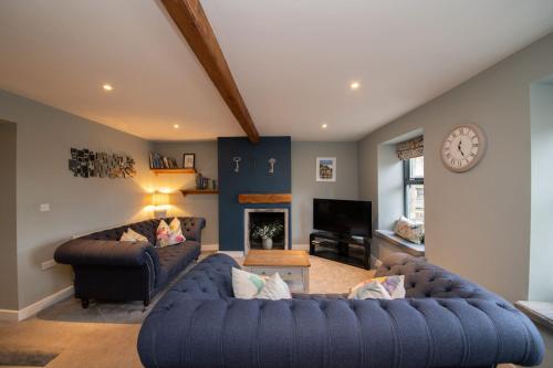 a living room with two couches and a clock at The Lookout Holmfirth in Holmfirth