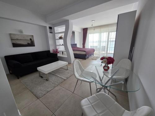 a living room with a glass table and white chairs at Tudor S Residence Mamaia in Văleni