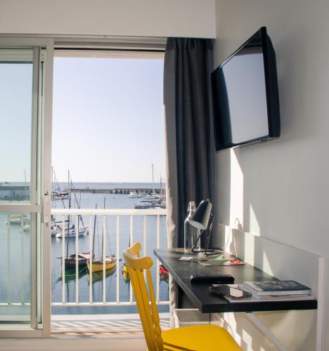 a room with a desk with a computer and a balcony at Logis Hotel Du Port in Plobannalec-Lesconil