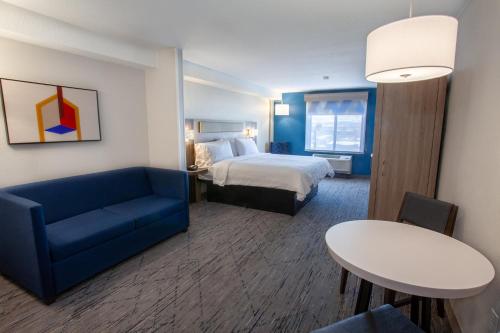 a hotel room with a bed and a blue couch at Holiday Inn Express & Suites Logan by IHG in Logan