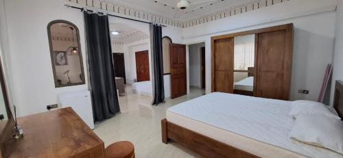 a bedroom with a bed and a table and a mirror at Waterfront in Muscat