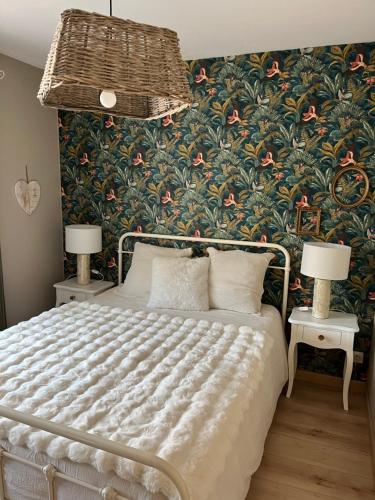 a bedroom with a bed with a floral wallpaper at le gite de sandrine in Réville