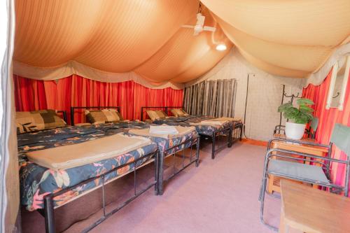 a room with four beds and red curtains at Zero Degree Camps in Joshīmath