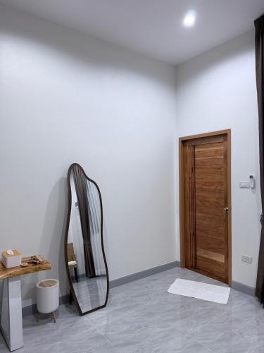 a mirror in a room with a wooden door at KlomKlom garden home in Ban Tha Kham